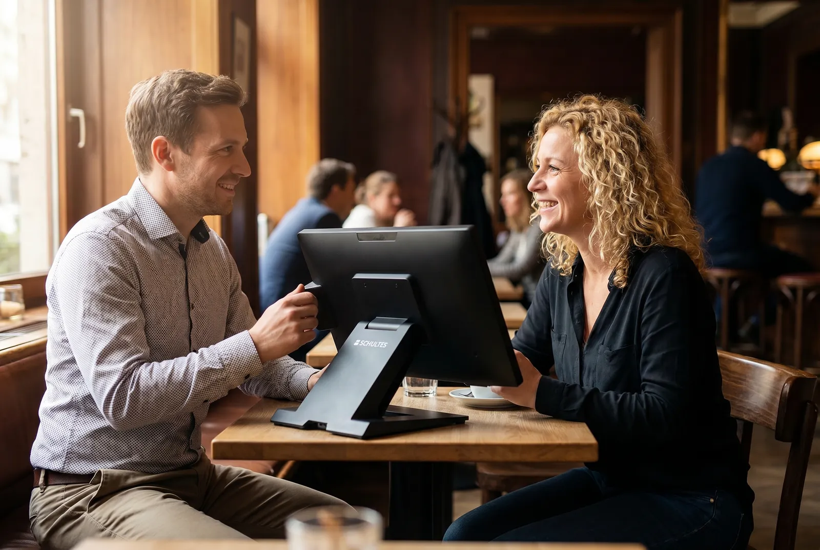 IT-Berater und Gastronomin im Gespräch an einer SCHULTES Touch-Kasse mit bluepos® in einem Düsseldorfer Bistro